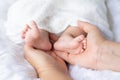 Mother Hand hold Cute newborn foot baby girl in white blanket onÃÂ nurseryÃÂ bed.Adorable new born child people